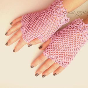 May include: A pair of pink crocheted fingerless gloves with a delicate lace trim. The gloves are made of a fine mesh material and have a light, airy feel.