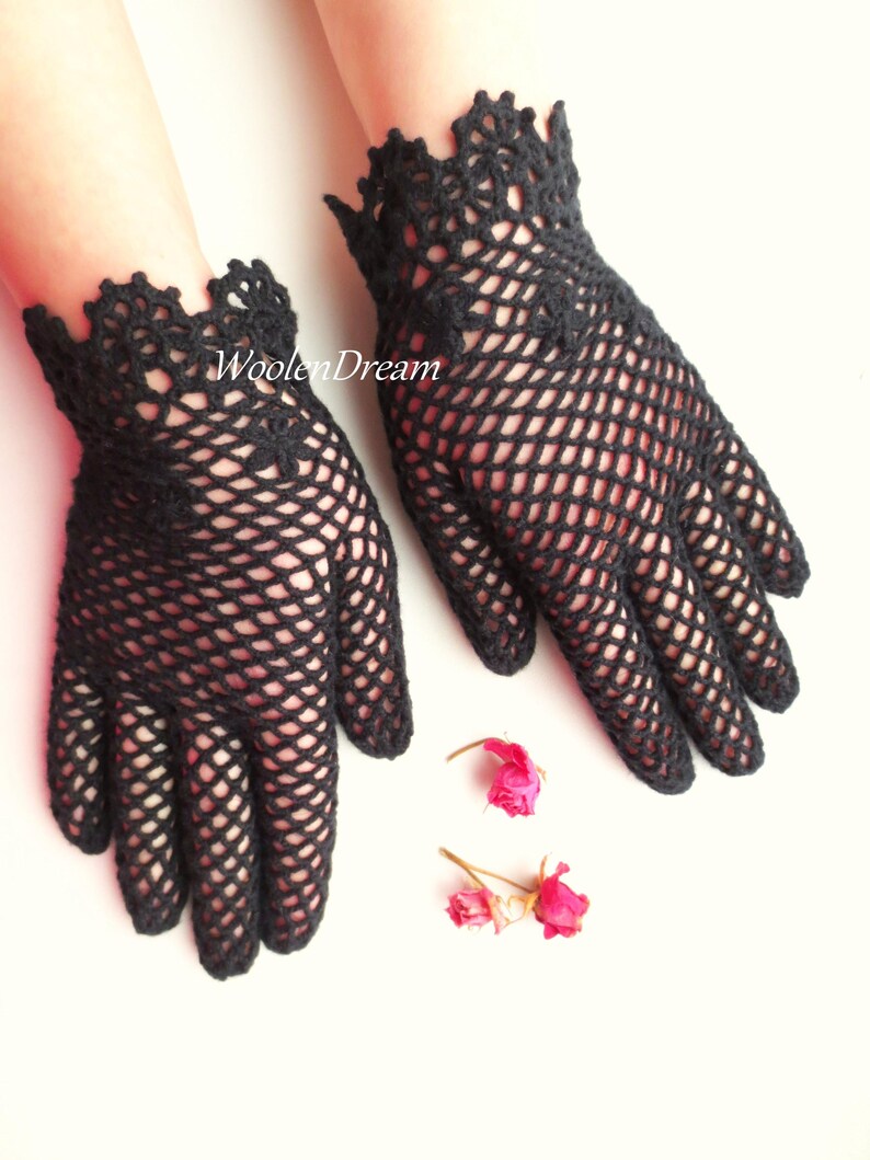 Puede incluir: Un par de guantes de ganchillo negros con un delicado patr&oacute;n de encaje. Los guantes son sin dedos y tienen un borde festoneado.