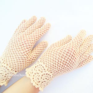 May include: A pair of cream-coloured crocheted gloves with a delicate lace pattern at the wrist.
