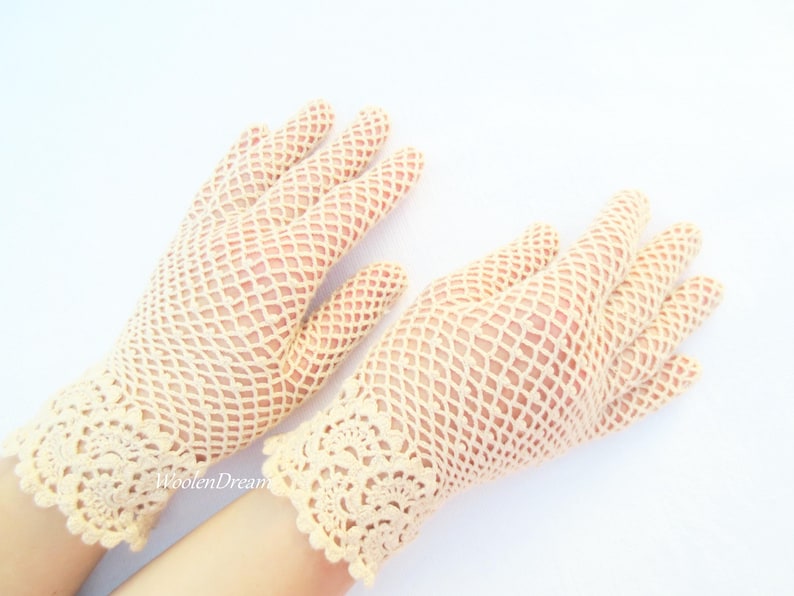 May include: A pair of cream-coloured crocheted gloves with a delicate lace pattern at the wrist.