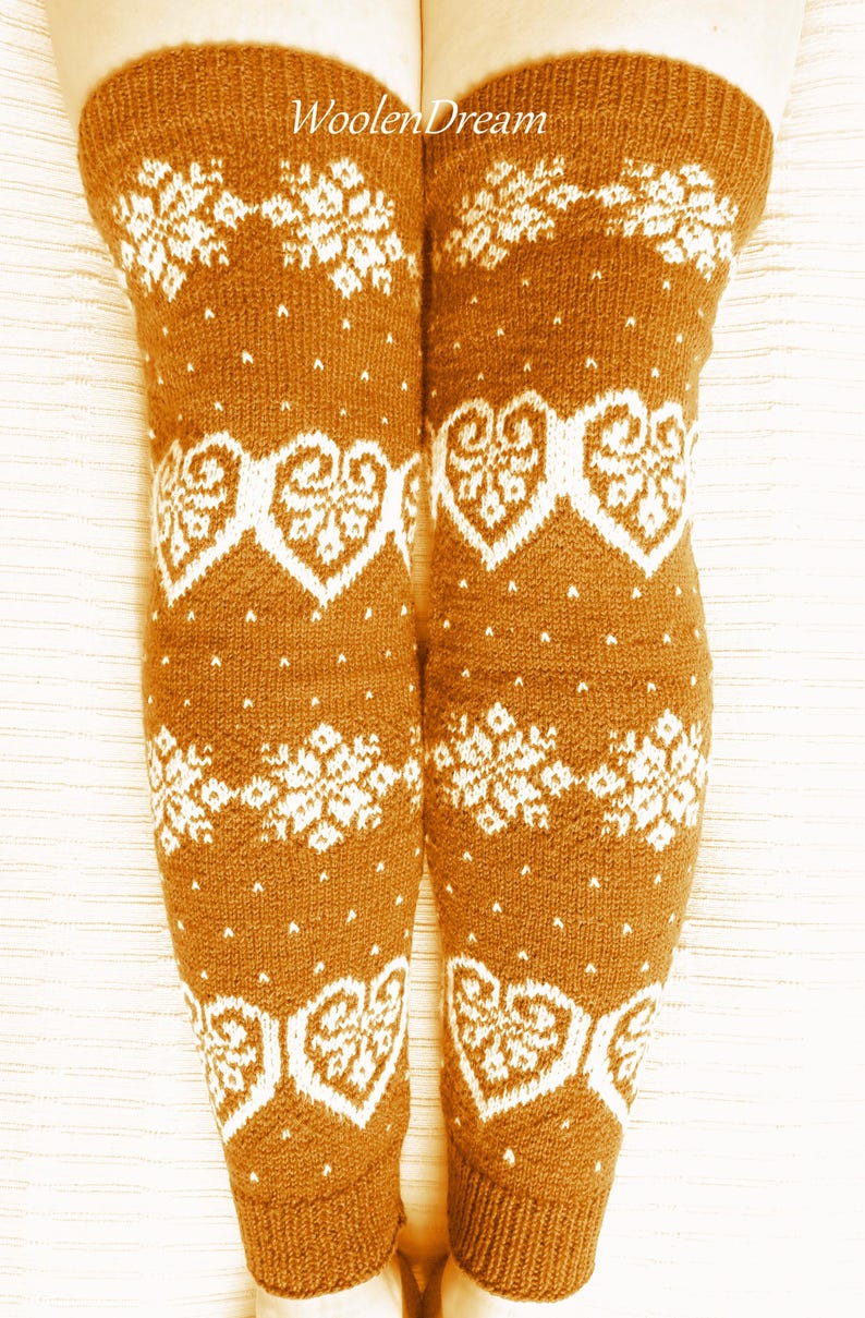 May include: Knee-high brown knit socks with white snowflake and heart patterns. The socks have a ribbed cuff and are visible from the knees down. The text "WoolenDream" is printed on the socks.