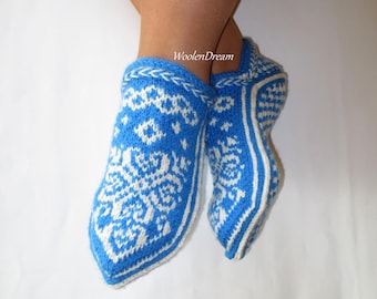 May include: Blue and white knitted slipper socks with a geometric pattern. The socks are folded down at the top and have a white trim.