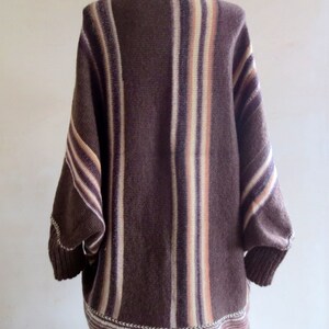 May include: A brown and cream striped knitted cardigan with a long, loose fit. The cardigan has a V-neck and a ribbed hem.