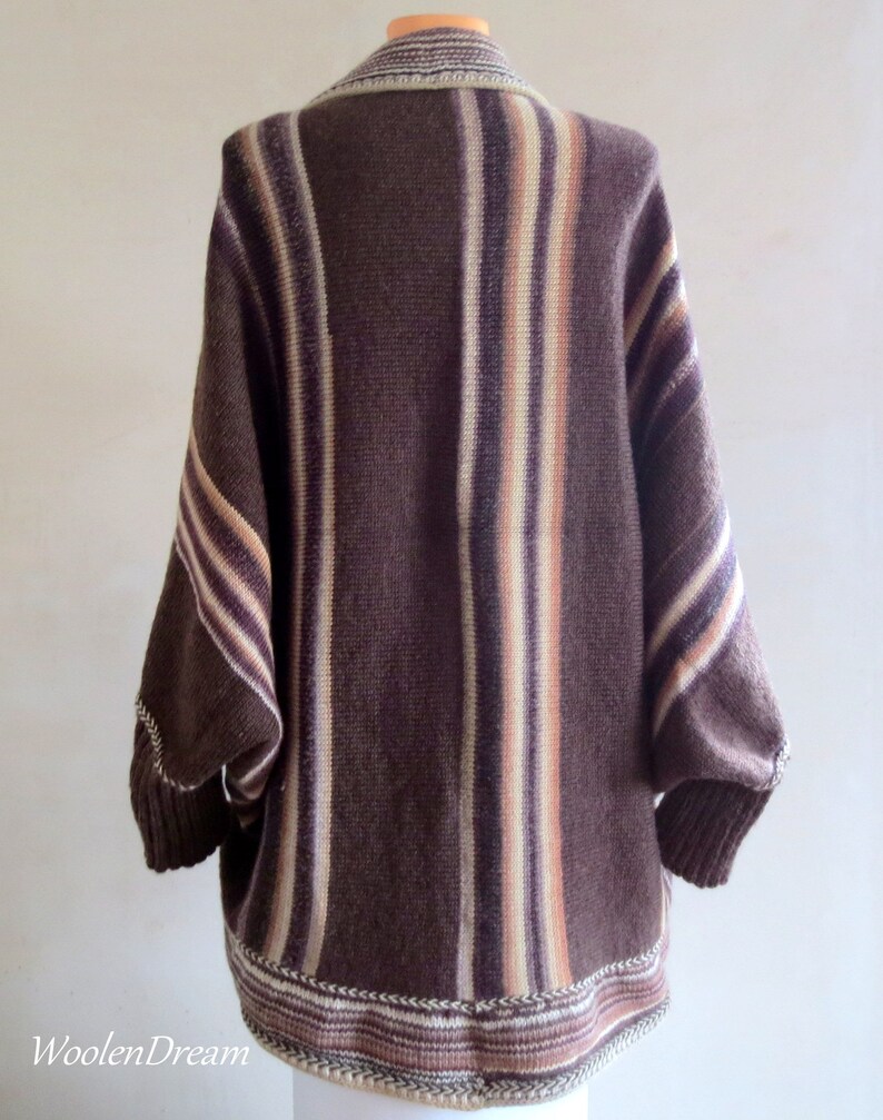 May include: A brown and cream striped knitted cardigan with a long, loose fit. The cardigan has a V-neck and a ribbed hem.