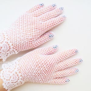 May include: A pair of white lace gloves with a delicate floral pattern at the wrist. The gloves are made of a fine mesh fabric.