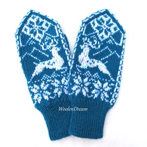 May include: A pair of teal blue knitted mittens with a white snowflake and deer pattern. The mittens have a folded cuff and the text "Woolen Dream" is printed on the cuff.