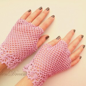 May include: A pair of pink crocheted fingerless gloves with a delicate lace pattern at the wrist.
