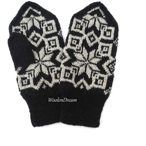 以下が含まれることがあります： 雪の結晶模様の黒と白のニットミトン。ミトンはウール製で、柔らかく温かい感触です。ミトンには「WoolenDream」の文字が見えます。