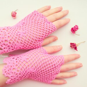 May include: A pair of pink crocheted fingerless gloves with a delicate lace pattern. The gloves are made of a lightweight, breathable material and are perfect for adding a touch of femininity to any outfit.