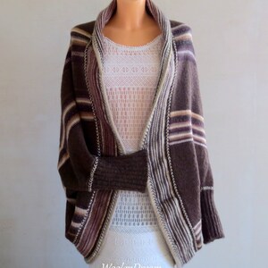 May include: A brown striped cardigan with a wide, open neckline. The cardigan has a relaxed fit and is made of a soft, knitted fabric.