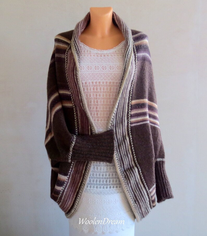 May include: A brown striped cardigan with a wide, open neckline. The cardigan has a relaxed fit and is made of a soft, knitted fabric.