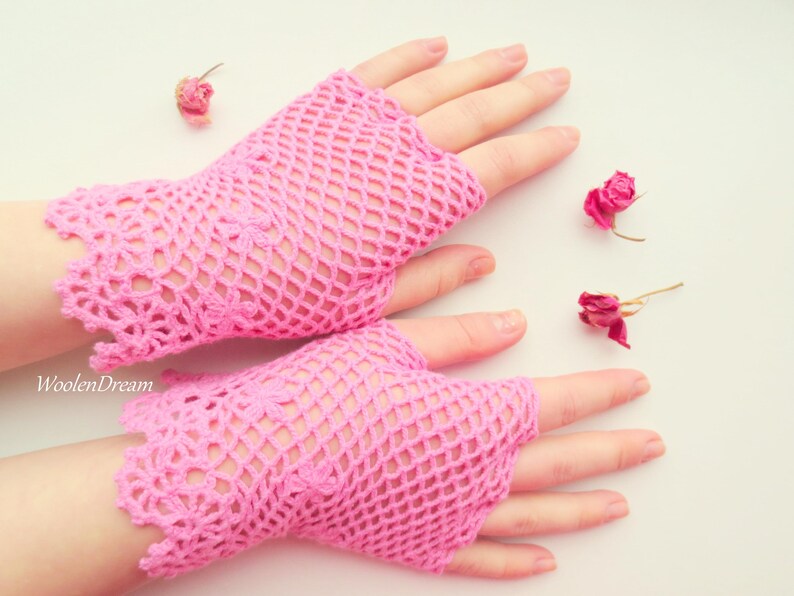 May include: A pair of pink crocheted fingerless gloves with a delicate lace pattern. The gloves are made of a lightweight, breathable material and are perfect for adding a touch of femininity to any outfit.
