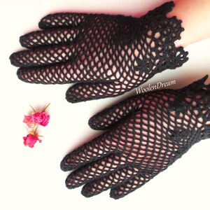 Puede incluir: Un par de guantes de ganchillo negros con un delicado patr&oacute;n de encaje. Los guantes est&aacute;n hechos de una tela fina y de tejido abierto y tienen un estilo ajustado.