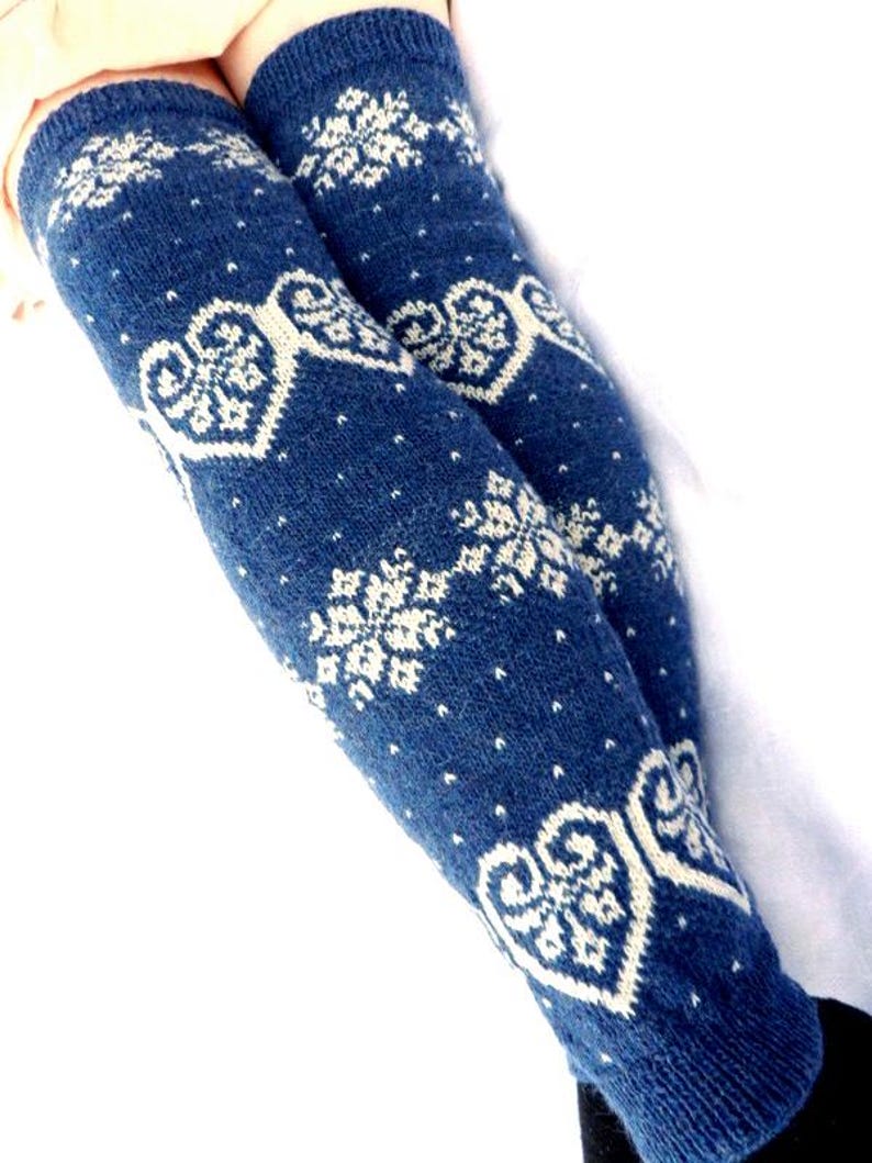 May include: A pair of blue knit leg warmers with white snowflake and heart patterns. The leg warmers are made of a soft, textured material and are designed to be worn over the lower legs.