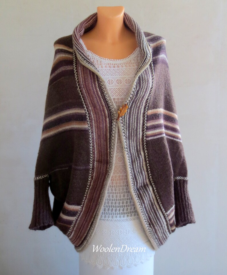 May include: A brown and white striped knitted cardigan with a shawl collar and a wooden button closure. The cardigan has a relaxed fit and is made of a soft, comfortable material.