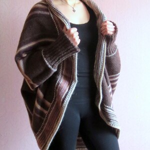 May include: A brown and cream striped cardigan with a long, loose fit. The cardigan has a wide, open collar and a ribbed knit texture.