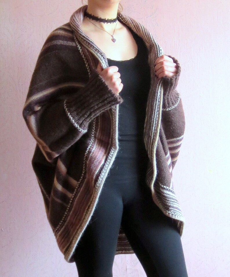 May include: A brown and cream striped cardigan with a long, loose fit. The cardigan has a wide, open collar and a ribbed knit texture.