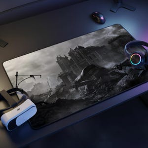 May include: A large rectangular gaming mouse mat with a grayscale apocalyptic cityscape design. A VR headset, headphones, and a mouse are visible on the desk. The mat provides a smooth surface for precise mouse movements.