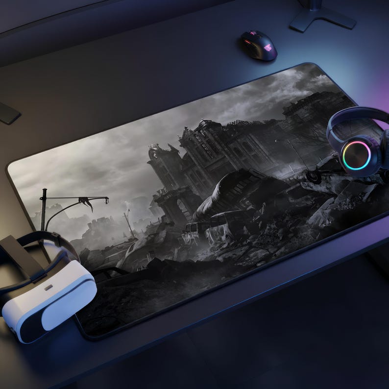 May include: A large rectangular gaming mouse mat with a grayscale apocalyptic cityscape design. A VR headset, headphones, and a mouse are visible on the desk. The mat provides a smooth surface for precise mouse movements.