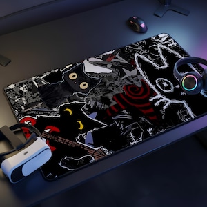 May include: A rectangular desk mat featuring a dark, graphic illustration with black cats, skeletal figures, and red spiral patterns. The design includes white line art of a cat face on the right side, set against a black background with various abstract motifs.
