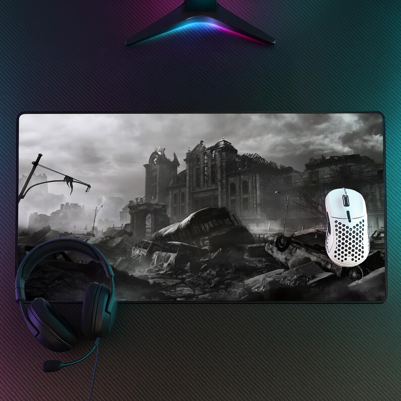 May include: A gaming setup featuring a black and white mouse, a black headset, and a large mousepad with a grayscale apocalyptic city scene. The mousepad is rectangular and the mouse is white with black accents.