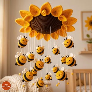 May include: A crochet nursery mobile featuring a large, central sunflower with a dark brown center and bright yellow petals. Hanging from the flower are numerous small, stuffed crochet bees with yellow and black stripes and white wings.
