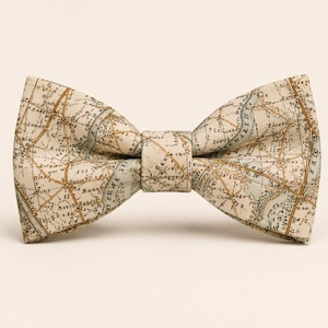 May include: A cream-colored bow tie featuring a vintage map design in shades of brown and blue. The bow tie is tied in the center and has a classic butterfly shape, suitable for formal occasions or adding a touch of flair to an outfit.
