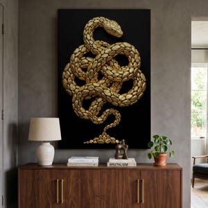 Peut inclure: Une œuvre d'art murale rectangulaire représentant un serpent doré en trois dimensions enroulé dans un nœud complexe sur un fond noir uni. Le serpent est composé de nombreux petits segments arrondis en forme de galets avec une finition dorée.