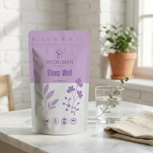 Puede incluir: Una bolsa lavanda y blanca con la etiqueta "HYOOMEN Sleep Well" con ilustraciones florales. Un vaso de agua con una ramita de vegetación y un paño beige están junto a la bolsa. La bolsa contiene 30 dosis diarias.
