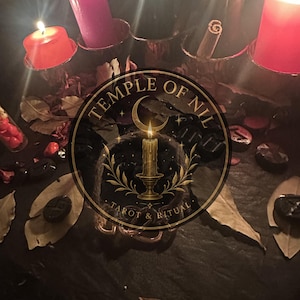 May include: A collection of four lit candles in red, pink, and black, arranged with scattered dried leaves and dark stones. A circular logo with the text TEMPLE OF NIL TAROT & RITUAL and a central candle illustration is overlaid on the scene.