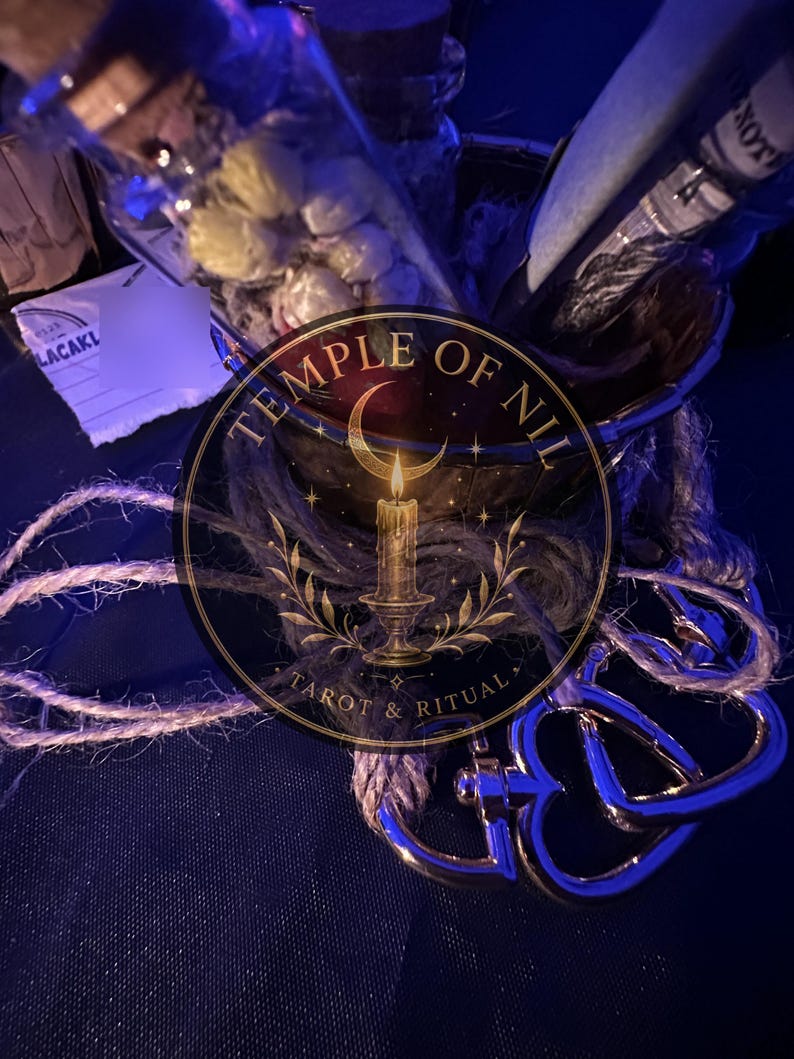 May include: A glass bottle filled with small white dried flowers, a dark metal container, and a silver-toned metal clasp attached to a piece of natural jute twine. The image features a circular logo with the text Temple of Nil Tarot & Ritual.
