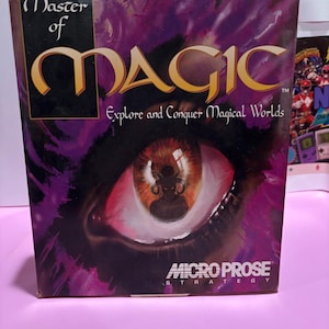 Puede incluir: Una caja rectangular de videojuego para Master of Magic, que presenta un ojo grande y detallado con una silueta con cuernos reflejada en el iris. El fondo es un degradado de color púrpura intenso y negro. El texto dice Master of Magic Explore and Conquer Magical Worlds y MicroProse Strategy.