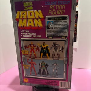 May include: Deluxe Edition Iron Man action figure box. The box is gray and purple with the Marvel Comics logo. The box is 10 inches tall, fully poseable, and includes accessories. The box features images of Iron Man, Mandarin, War Machine, Human Torch, Dr. Doom, and Silver Surfer.