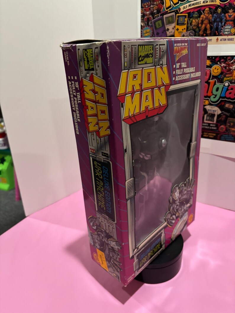 May include: A boxed Iron Man action figure from Marvel Comics. The box is purple and silver with the Iron Man logo and the words "Deluxe Edition War Machine." The figure is 10 inches tall and fully poseable.