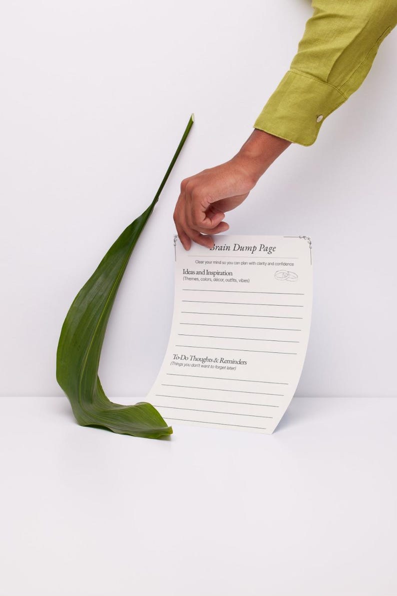 K&ouml;nnte beinhalten: Ein wei&szlig;es Blatt Papier mit der &Uuml;berschrift Brain Dump Page, das Abschnitte f&uuml;r Ideas and Inspiration sowie To-Do Thoughts and Reminders und horizontale Schreiblinien enth&auml;lt. Das Papier liegt neben einem einzelnen, langen, gebogenen gr&uuml;nen Blatt.