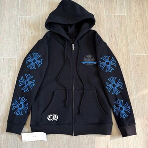 Puede incluir: Sudadera negra con cremallera, capucha y bolsillos delanteros. Las mangas presentan dise&ntilde;os florales azules y el pecho un emblema similar. La sudadera tiene una cremallera plateada y las letras "CH" en blanco.
