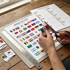 May include: A person is cutting out a small Mexican flag from a sheet of paper labelled "WORLD CUP 2026". The paper displays various national flags. A metal ruler and other flag cutouts are also visible.