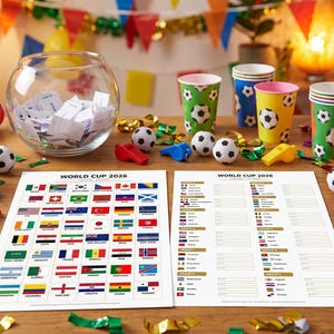 May include: A celebratory display featuring soccer-themed party items. Includes paper cups with soccer ball patterns, miniature footballs, whistles, and two sheets with the text "WORLD CUP 2026" and flags of participating nations. A glass bowl contains folded papers.