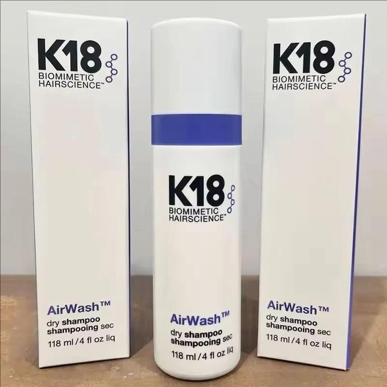 May include: A white cylindrical bottle of K18 Biomimetic Hairscience AirWash dry shampoo with a blue band, flanked by two matching white rectangular product boxes. Each item displays the text K18 Biomimetic Hairscience, AirWash, and 118 ml / 4 fl oz liq.