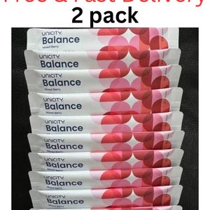 Pode incluir: Um pacote de dois sach&ecirc;s de suplemento alimentar Unicity Balance Mixed Berry. Cada sach&ecirc; retangular branco apresenta o logotipo Unicity Balance em texto azul escuro e um padr&atilde;o de c&iacute;rculos rosa e vermelhos sobrepostos no lado direito.