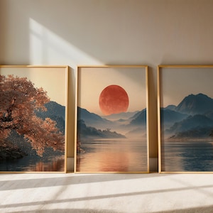 Peut inclure: Trois cadres muraux verticaux représentant des paysages. L'image de gauche montre un arbre au feuillage orange près de l'eau. L'image centrale affiche un grand soleil rouge au-dessus de montagnes brumeuses et d'un lac. L'image de droite montre des montagnes bleues.