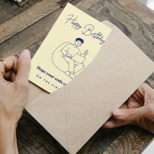 May include: A pale yellow birthday greeting card featuring a dark blue line drawing of a person sitting in a beanbag chair using a laptop with a thumbs up. The text reads Happy Birthday and Hope your code compiles ON THE FIRST TRY.
