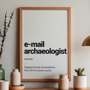 Puede incluir: Un marco de madera rectangular que contiene una impresión blanca con el texto negro e-mail archaeologist (NOUN) Digging through conversations from 2019 to prove a point. La impresión se muestra en orientación vertical con un diseño limpio.
