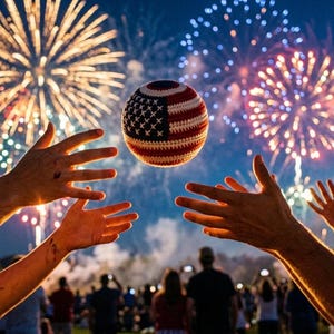 May include: A festive scene with a crocheted ball featuring the American flag design, suspended in mid-air. Fireworks burst in the background, and people reach for the ball. The night sky is dark blue, and the overall mood is celebratory.