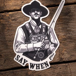 May include: A black and white sticker featuring a person wearing a wide-brimmed hat, a collared shirt, a vest, and a fishing chest pack. The person holds a fly fishing rod and reel. The text SAY WHEN is printed at the bottom with HATCH-IT branding.