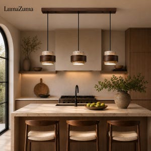 May include: A linear pendant light fixture featuring three cylindrical lamps suspended from a dark wood rectangular ceiling mount. Each lamp consists of a textured stone-like upper and lower section with a dark wood band in the center.