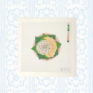 May include: A square needlepoint canvas featuring a cross-stitched dragon fruit design in the center. The fruit has a white interior with black seeds, surrounded by green leaves and yellow segments on a pink circular background. A color key is on the right.
