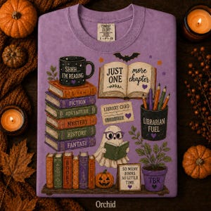 May include: A purple crewneck t-shirt featuring a graphic print of stacked books labeled with genres, a mug with the text SHHH... I'M READING, an open book with the text JUST ONE more chapter, a ghost reading a book, and a pencil holder labeled LIBRARIAN FUEL.