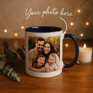 Peut inclure: Un mug en céramique blanche avec un intérieur et une anse bleu foncé. L'avant du mug présente une photographie imprimée d'une famille de quatre personnes, deux adultes et deux enfants. Au-dessus du mug, le texte "Your photo here" est écrit.