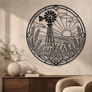 May include: A circular black metal wall art piece featuring a detailed cutout design of a rural landscape. The scene includes a central windmill, a rising sun with radiating beams, clouds, and stalks of wheat in the foreground, all enclosed in a frame.